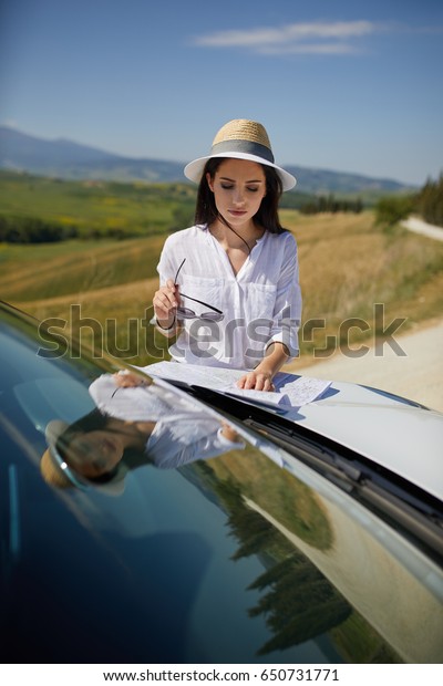 A tourist with a map at the car checks the\
route to the destination