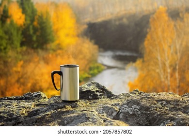 Tourist Metal Mug With A Hot Drink Stands On A Stone Against The Background Of A Beautiful Autumn Yellow Forest And River, Rocks, Mountains, Tourism, Romance, Steam, Fume