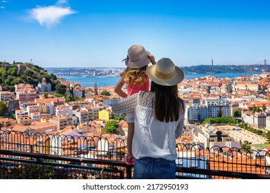 A tourist mother and her little daughter enjoy the view of the beautiful cityscape of Lisbon, with the colorful houses and roofs, Portugal