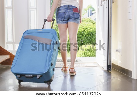 tourist nn T-shirt, shorts and sandals with blue vacation suitcase exits through the front door.