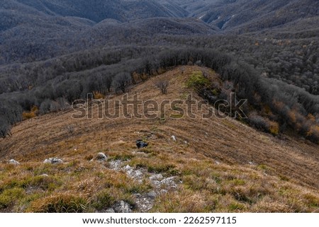 A tourist on a hike along the picturesque peaks at an altitude of 1000m. View from a great height in a picturesque place of the Caucasus. Caucasian mountain landscape with steep rocky cliffs. 