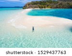 Tourist on a tropical beach with blue water and palm trees - Coron, Philippines
