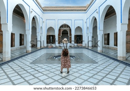 A tourist with open arms at El Bahia. the palace which is visited by tourists from world on 24 August 2014 in Marrakesh, Morocco. It is an example of Eastern Architecture from the 19th century.