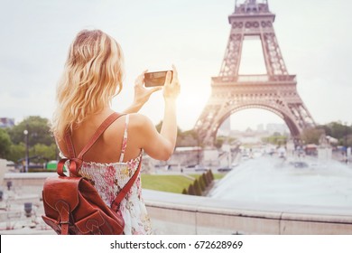 tourist in Paris visiting landmark Eiffel tower, sightseeing in France, woman taking photo on mobile phone