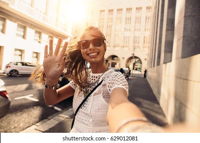 Tourist posing for a selfie in a street. Vlogger recording content for her travel vlog.