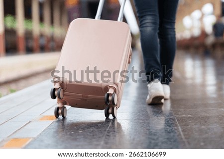 Tourist pulling a rolling suitcase while walking through a bustling train station, eagerly preparing for an exciting journey ahead