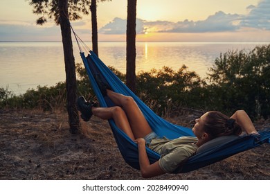 Tourist relaxing in hammock next to lakeside