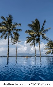 Turista relajante en piscina infinita con vista al mar y palmeras