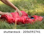 Tourist rolling red sleeping bag outdoors, closeup