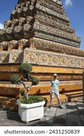 Tourist shild, cute kid. Wat Phra Chetuphon Vimolmangklararm Rajwaramahaviharn (Wat Pho) Buddhist temple complex in Bangkok city, Thailand. Religious traditional national Thai architecture. Landmark