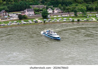 A tourist ship sailing on the river Rhine in western Germany, visible buildings and caravans on the river bank.