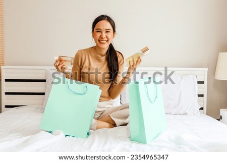 Tourist shopper beautiful asian woman sitting and relaxing on hotel bed, happy traveling shopping, cosmetics, french perfume, best selling products duty free with discount promotion in shopping mall.