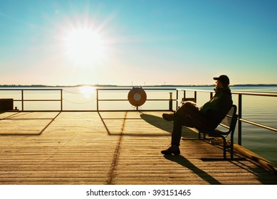 Tourist Sit On Wharf Construction And Enjoy Morning At Sea. Sunny Clear Blue Sky, Smooth Water Level