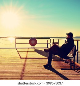 Tourist Sit On Wharf Construction And Enjoy Morning At Sea. Sunny Clear Blue Sky, Smooth Water Level