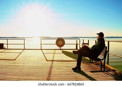 Tourist Sit On Wharf Construction And Enjoy Morning At Sea. Sunny Clear Blue Sky, Smooth Water Level