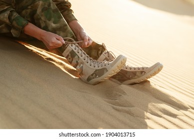 A Tourist Sits In Army Clothes And Beige Boots In The Desert. Caucasus, Russia