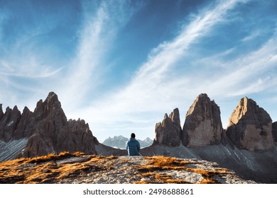 Tourist sitting on rock edge at Three Peaks of Lavaredo track on autumn season. National Park Tre Cime di Lavaredo, Dolomite Alps mountains, Trentino Alto Adige region, Sudtirol, Dolomites, Italy - Powered by Shutterstock