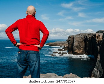 Tourist standing and enjoy view of stunning mini cliff in county Clare, Ireland. Travel and tourism. Bald man in red shirt, slim athletic body type in nature setting. - Powered by Shutterstock