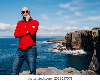 Tourist standing and enjoy view of stunning mini cliff in county Clare, Ireland. Travel and tourism. Bald man in red shirt, slim athletic body type in nature setting. - Powered by Shutterstock