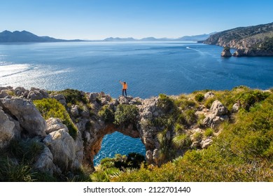 Tourist standing on the natural stone bridge near the sea. Formentor. Mallorca.