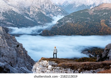 A tourist stands over the fog at the edge of a cliff in the Dolomites mountains. Location Auronzo rifugio in Tre Cime di Lavaredo National Park, Dolomites, Trentino Alto Adige, Italy