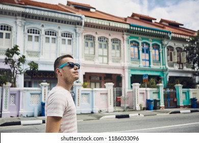 Tourist With Sunglasses Walking Throught Old Street In Singapore. Colorful Houses With Combined Malay, Chinese, Indian And Western Architecture And Culture.