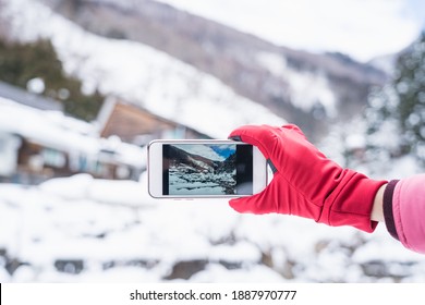 Tourist take picture of snow mountain while holding smartphone with red glove - Powered by Shutterstock