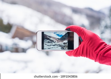 Tourist take picture of snow mountain while holding smartphone with red glove - Powered by Shutterstock