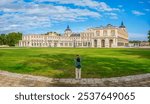 A tourist taking a photo of the main facade of the Royal Palace of Aranjuez, a historic residence of the Spanish monarchy, located in Aranjuez, Madrid, Spain.