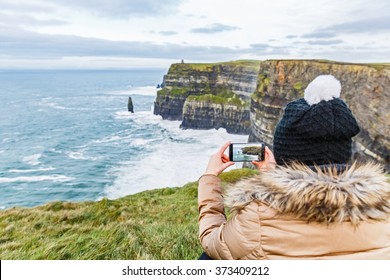 Tourist, der ein Foto mit Smartphone über Cliffs of Moher macht