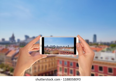 A tourist is taking a photo of view from above of the Poland capital - Warsaw in summer day on a mobile phone