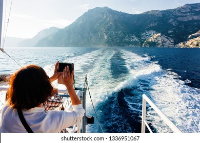 Tourist Taking Photos On Camera During Cruise Excursion Tour On Boat In Tyrrhenian Sea In Positano Town Of Amalfi Coast, Italy, Summer. Beautiful Mediterranean View Near Sorrento. Travel And Tourism