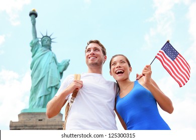Tourist travel couple at Statue of Liberty, New York City, USA. Multiracial tourist couple on summer vacation holidays. Asian woman holding American flag smiling happy. - Powered by Shutterstock