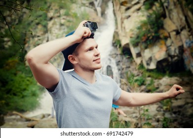 Tourist Traveler With An Action Camera Go On His Head In The Background Waterfall In Vietnam. Concept Of Extreme Holidays In The Mountains.