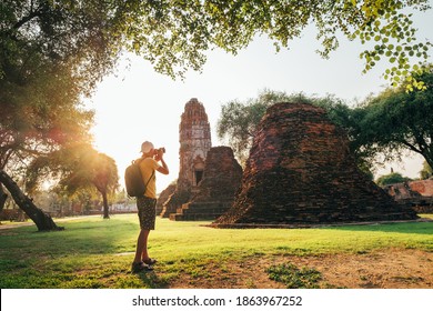 Tourist traveler with a backpack taking a photo of ancient Wat Ratchaburana Buddhist temple in holy ancient Ayutthaya city, Thailand - Powered by Shutterstock