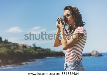 Tourist traveler photographer making pictures seascape on vintage photo camera on background yacht and boat piar, hipster girl enjoying peak nature holiday, mockup ocean waves view, blurred backdrop