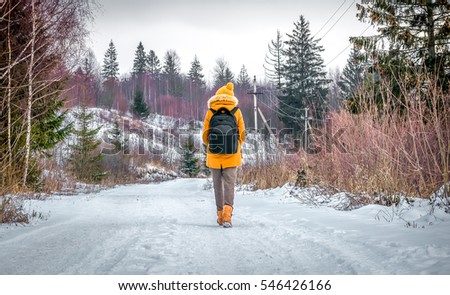 tourist traveler is winter in the woods with a backpack on a snowy road