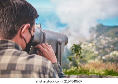 Tourist using binoculars looking at the city Caracas from an observation point in the Avila. Man enjoying vacation during summer. landscape concept
