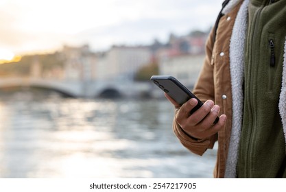 Tourist using smartphone while enjoying sunset view over river and city - Powered by Shutterstock