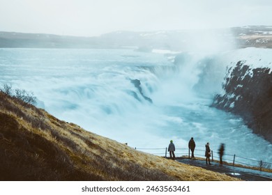 Tourist visit stand on viewpoint Gullfoss waterfall in Iceland, Cinematic beautiful majestic winter waterfall cover by snow and ice. Slow motion. Purple Sunset sky - Powered by Shutterstock