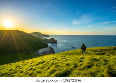 Tourist Walking Across The Coast Of Durdle Door In Dorset, Jurassic Coast, England, UK 