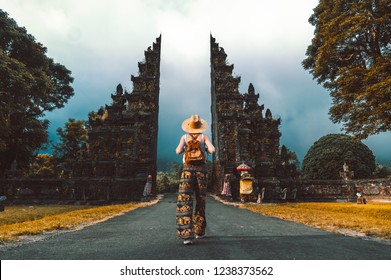 Tourist woman with backpack at vacation walking through the Hindu temple in Bali in Indonesia - Shutterstock ID 1238373562