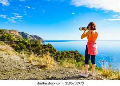 Tourist Woman With Camera Taking Travel Photo From Seaside Cliff, Mediterranean Coastal Landscape. Summer Holiday Trip.