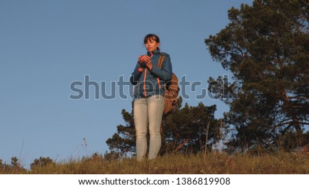 tourist woman drinking hot tea and watching sunset. girl traveler, stands on top of hill drinking coffee in glass from thermos. Adventurer rest after reaching goal. concept of freedom and dreams.