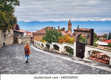 Tourist woman in hat with backpack at the street of Signagi town in Georgia