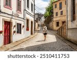 Tourist woman with hat walking through the old streets of the town of Mondenedo on the Camino de Santiago, Galicia.