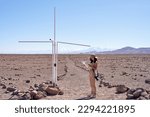 tourist woman holding and looking a map at milestone that marks the passage of the parallel of the Tropic of Capricorn through San Pedro de Atacama