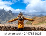 A tourist woman looking at Roque Nublo from a viewpoint with her arms open. Gran Canaria, Spain