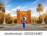 A tourist woman looks at the famous Arc de Triomf in Barcelona, Spain, on her sightseeing trip through the city during sunrise