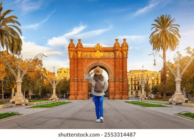 A tourist woman looks at the famous Arc de Triomf in Barcelona, Spain, on her sightseeing trip through the city during sunrise